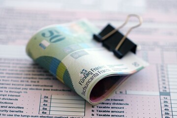 Swiss franc banknotes and tax form. The current francs money bills lies on tax return form