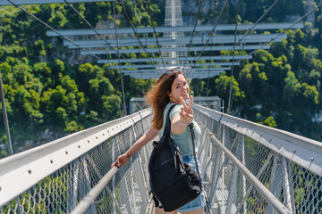 A young woman on a suspension bridge in a skypark in Sochi, summer travel and entertainment.