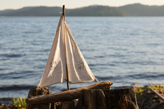 A toy sailboat outside near a lake. The small boat could float on the water and move with the wind. 