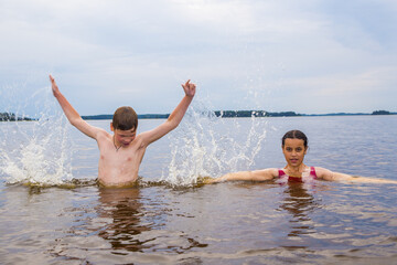 Children, boy and girl in red swimsuit swimming in the lake
