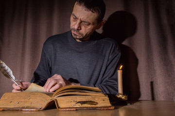 A man, European, 49 years old, reads an old book. Everyday life of the population of Russia.