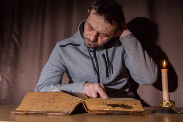 A man, European, 49 years old, reads an old book. Everyday life of the population of Russia.