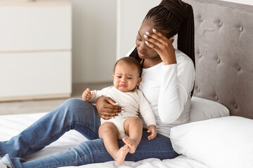 Postpartum Depression Concept. Portrait of tired African American woman sitting with her small...