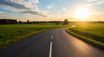 Fototapeta premium Serene Sunset Landscape: Winding Asphalt Road Through Lush Green Fields and Farmland