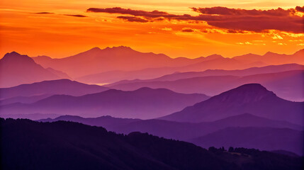 Layers of purple mountains fade into the sunset with an orange sky