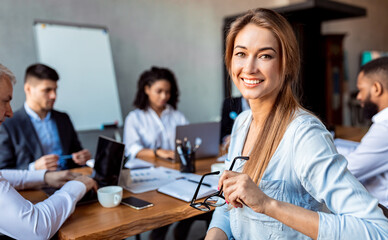 Business Career. Businesswoman Smiling To Camera Sitting On Corporate Meeting With Coworkers In Modern Office. Copy Space