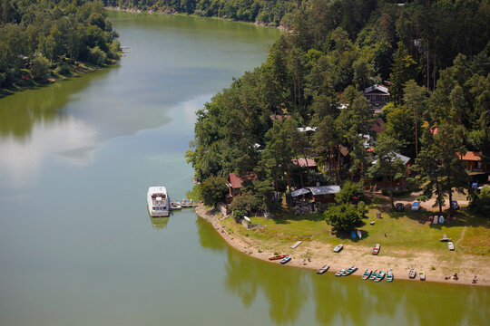 View from castle ruins Cornstejn of Vranovska dam with green water due to summer algae bloom, cottages and boats by the shore in Chmelnice area, peaceful holiday location in Czech countryside