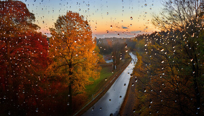 raindrops on window overlooking scenic autumn pathway at dusk