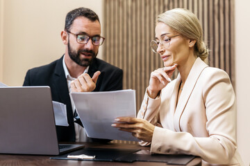 Business professionals engaged in a discussion while reviewing documents in a modern office...