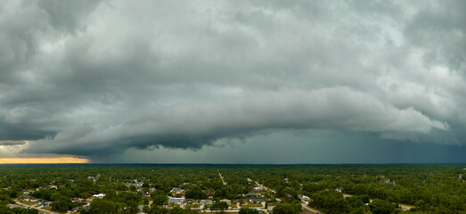 Dark stormy clouds forming on gloomy sky before heavy rainfall over suburban town area