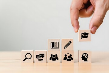 Hand placing a graduation cap icon block on a stack of wooden blocks representing education and learning concepts symbolizing achievement and knowledge acquisition