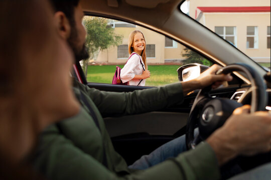Mother and father brought their daughter to school, schoolgirl smiling to parents, view from inside auto
