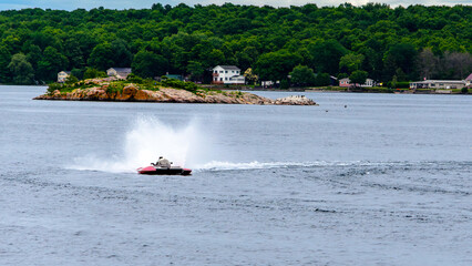 Fototapeta premium Single red and white hydroplane boat throwing spray on the water