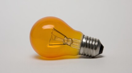 Unique orange light bulb with a vintage design, showcasing intricate filament details, lying on a smooth surface, representing creativity and innovation in lighting solutions
