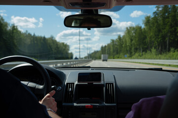 Driving car inside view. Man is holding steering wheel on highway road at daytime