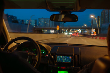 Driving car inside view. Man is holding steering wheel on city urban road at night