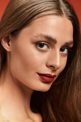 Fototapeta premium Beautiful young woman with long hair and striking features posing against a vibrant background