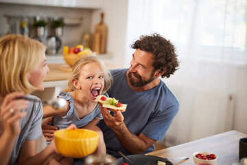 Family members share a delightful meal in a well-lit kitchen, laughing and engaging with each other...
