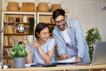 A man and woman engage in a productive conversation while reviewing documents together in a stylish...
