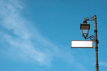 Vintage Street Lamp with Blank Sign Against Clear Blue Sky - Directional Lighting and Wayfinding Concept