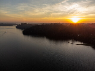 Orange sun setting between mountains behind large lake