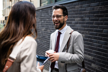 Businessman laughing with colleague holding coffee and tablet in the city