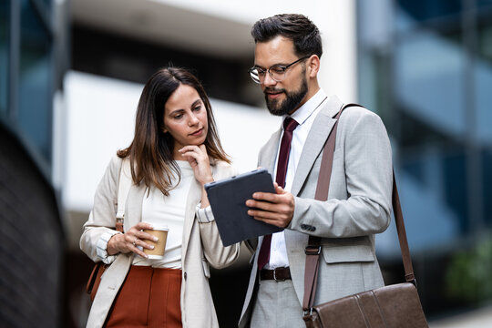 Businesspeople using digital tablet outdoors discussing work