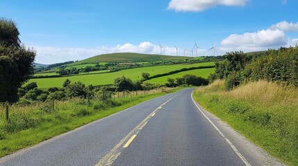 Fototapeta premium Country road, green hills, wind turbines, sunny day, Ireland