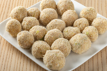 Crispy tuna potato croquettes with breadcrumb coating on white plate.