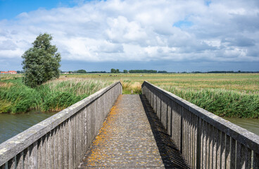 Fototapeta premium Perspective view over wooden bridge at the Uitkerkse Polders in Uitkerke, West Flanders, Belgium