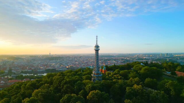 Witness the captivating sunrise over Prague from the Petrin Lookout Tower. The golden light illuminates the cityscape and surrounding gardens, creating a breathtaking view.