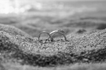 Wedding rings on the sand by the sea, black and white romantic scene