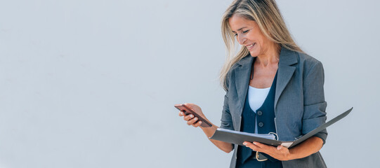 businesswoman with mobile phone and documents outdoors