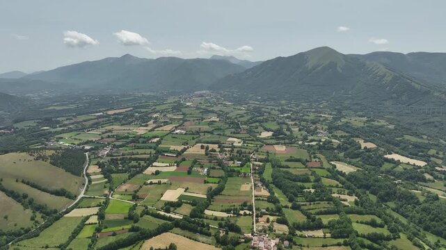 Expansive Farmland Valley Under Mountain Range Seen From Above
