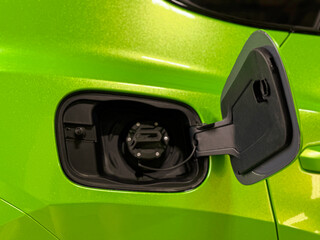 Neck of the fuel tank of a green car for refueling with gasoline fuel. An open fuel tank cap of a...