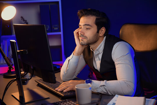 Feeling bored businessman waiting for analyzing market data or e-mail sending back to customer preparing created on sales channel online product service at neon dark light at late night time. Surmise. - Powered by Adobe