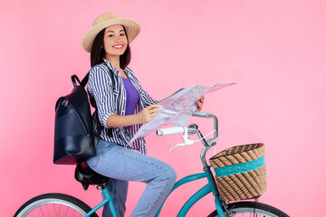 City Tour. Positive young asian lady riding bicycle and holding paper map. Charming woman wearing...