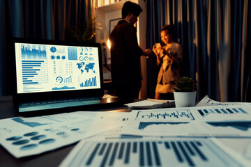 Setting on laptop showing business graph surrounded by paperwork marketing planning project on desk...