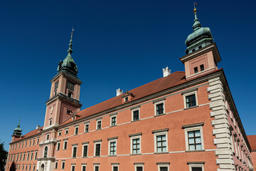 Tourists gather near Royal Castle in Warsaw, Poland under clear blue skies