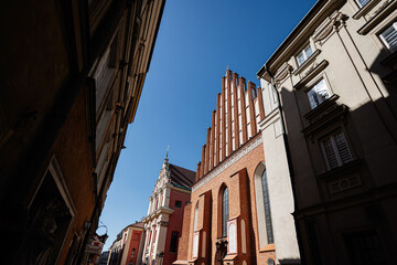 Historic St John's Archcathedral and old town street in Warsaw under blue sky