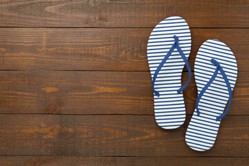 Striped blue flip flops on wooden background, top view