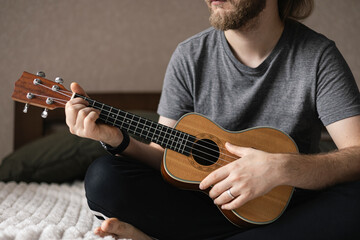 Man learns to play the ukulele. The concept of online learning, home education.