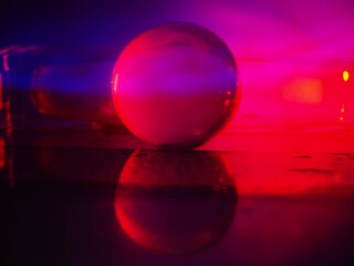 A clear glass ball is sitting on a pedestal. Colorful background. Abstract graphic background. Light effect. Planet in a space mood and feel.
