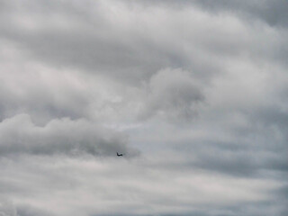 A plane is flying through a cloudy sky. The clouds are dark and heavy, giving the scene a moody and ominous atmosphere. Time to travel concept. Tourist industry.