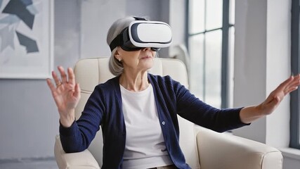 Senior woman wearing virtual reality headset is immersed in an engaging experience while seated in a stylish armchair, surrounded by modern decor and large windows, showcasing technology and comfort - Powered by Adobe