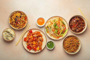 Assorted Chinese dishes, sweet and sour chicken, beef in sauce, noodles, fried rice, salad and wooden chopsticks. Chinese or Asian restaurant concept
