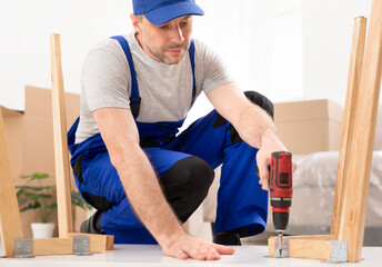 Furniture Repair And Assembly. Workman Fixing Table Using Electric Drill Assembling And Furnishing Home After Renovation Indoor