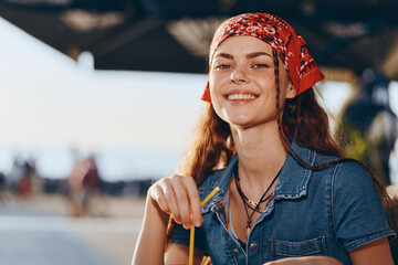 smiling woman enjoying summer drink outdoors with red bandana and denim shirt, natural light,...