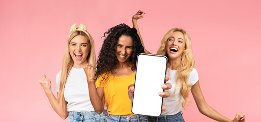 Carefree attractive millennial ladies in stylish casual outfits having fun together on pink studio...