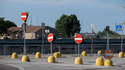 Multiple no-entry traffic signs with yellow barriers on street